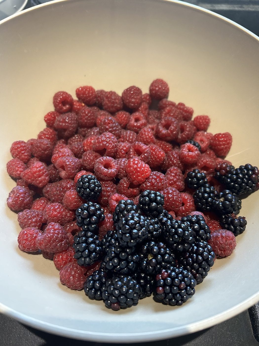 A bowl of freshly picked fall raspberries and blackberries